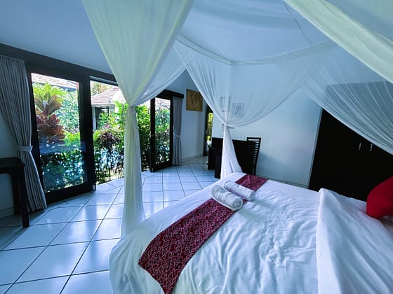 The bedroom at the Headlines House Ambary Ubud Villas consists of a queen bed, a large cupboard, 2 desks and chairs